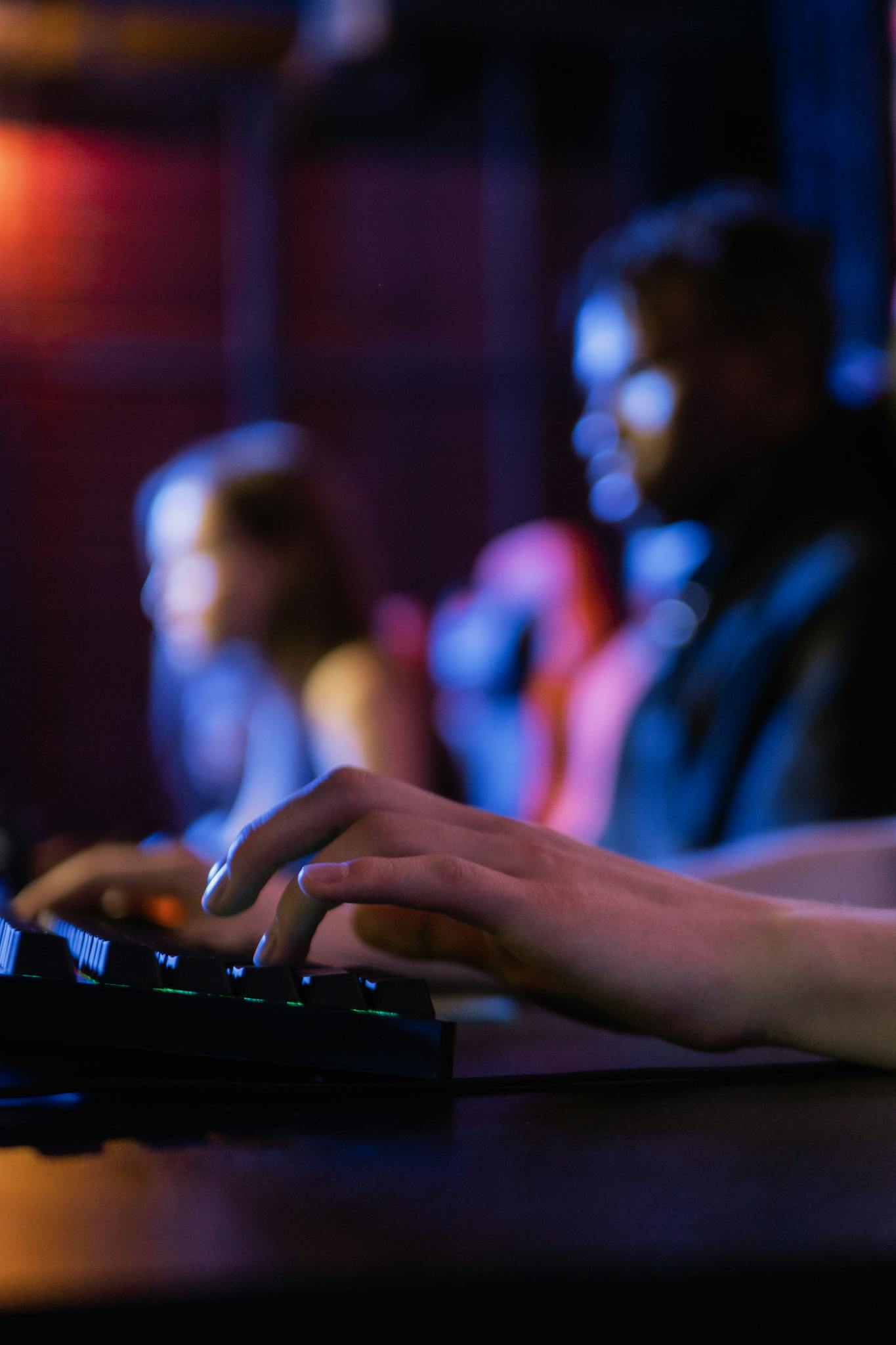 Close-up of hands typing on a keyboard during an intense gaming session in a dimly lit room.